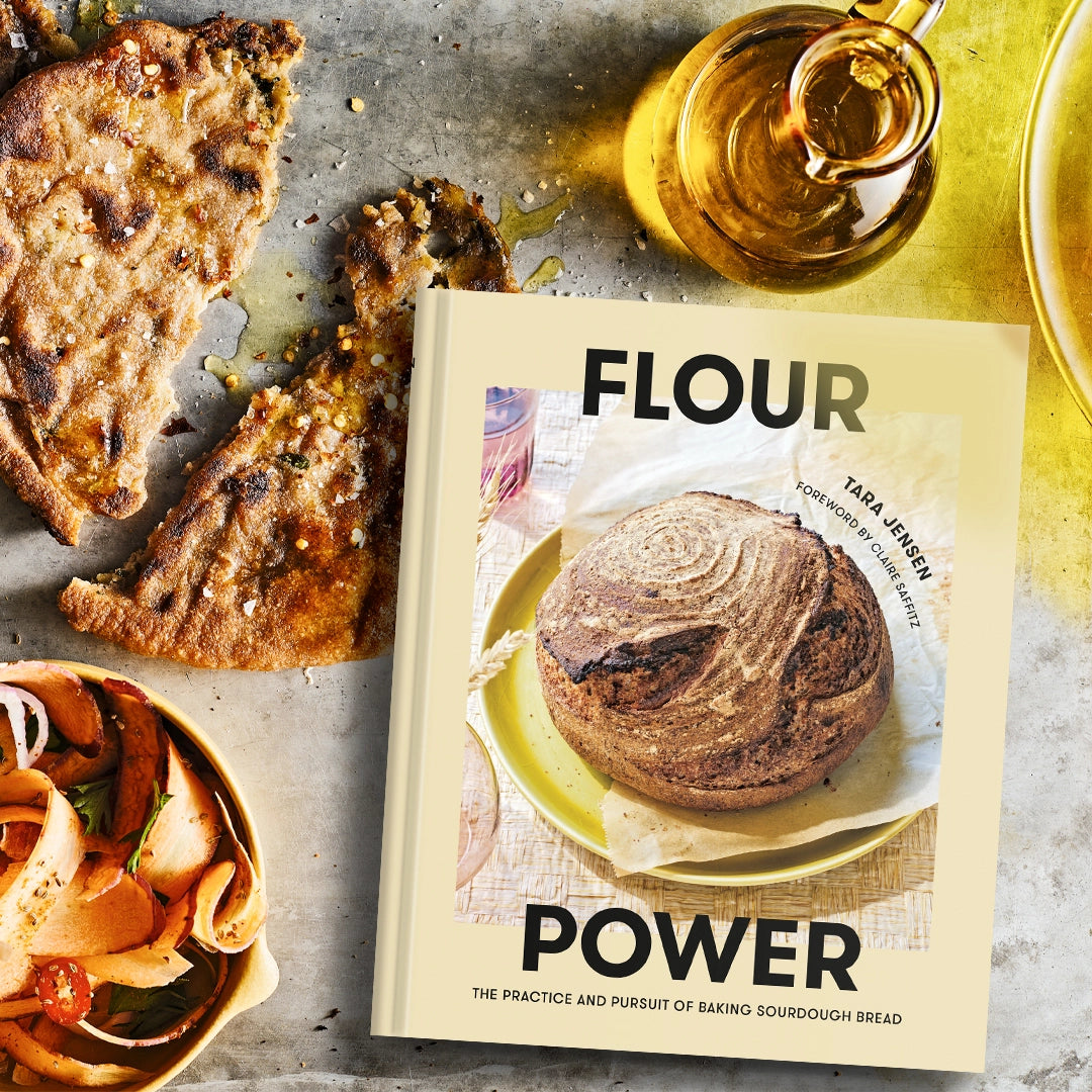 Book titled 'Flour Power' with bread and olive oil on a rustic surface