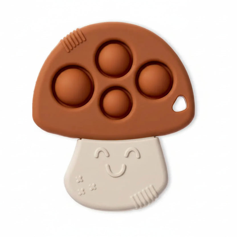 A mushroom-shaped baby teether or sensory toy with a brown cap featuring four raised bubble circles and a cream-colored stem with a smiling face, shown on a white background.