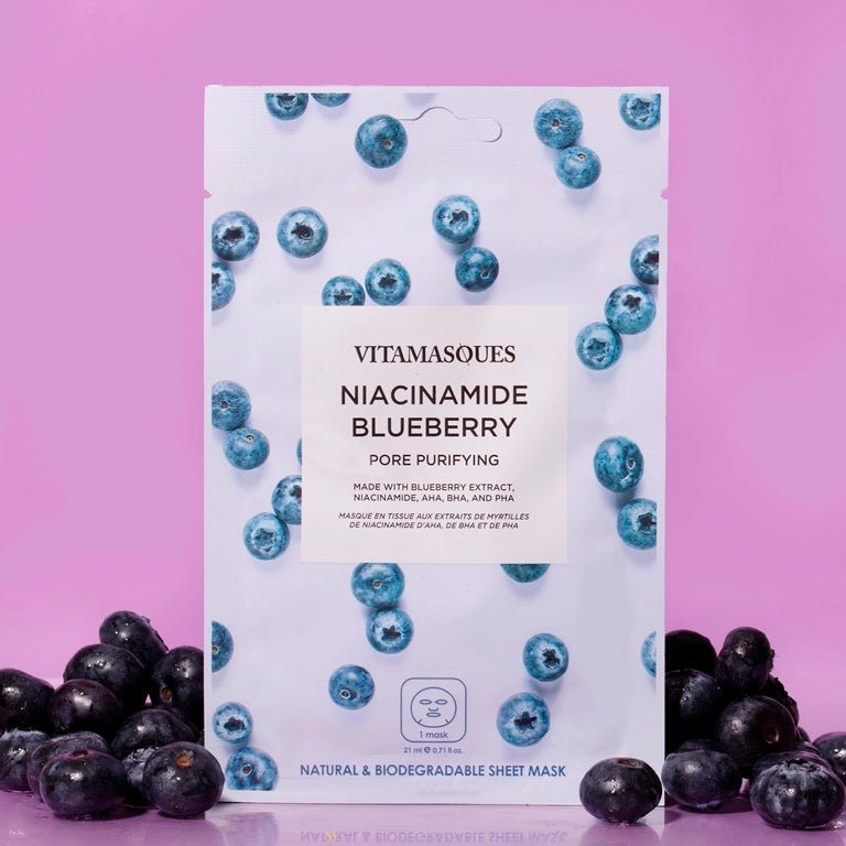 Vitamasques Niacinamide Blueberry sheet mask packaging on a pink background with blueberries.