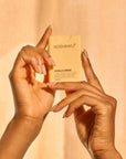 Hands holding a Noshinku Vanilla Creme product against a beige background