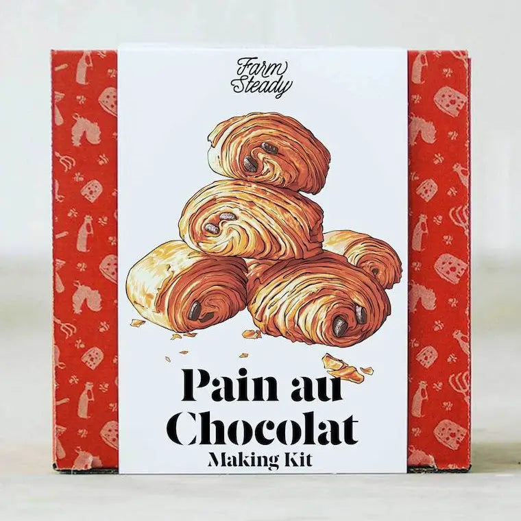 A boxed baking kit labeled 'Farm Steady' and 'Pain au Chocolat Making Kit,' with illustrated chocolate croissants on the front and red patterned side panels.