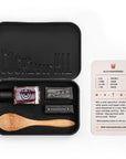 Cocktail kit with black tin, cocktail ingredients, and wooden spoon on a white background