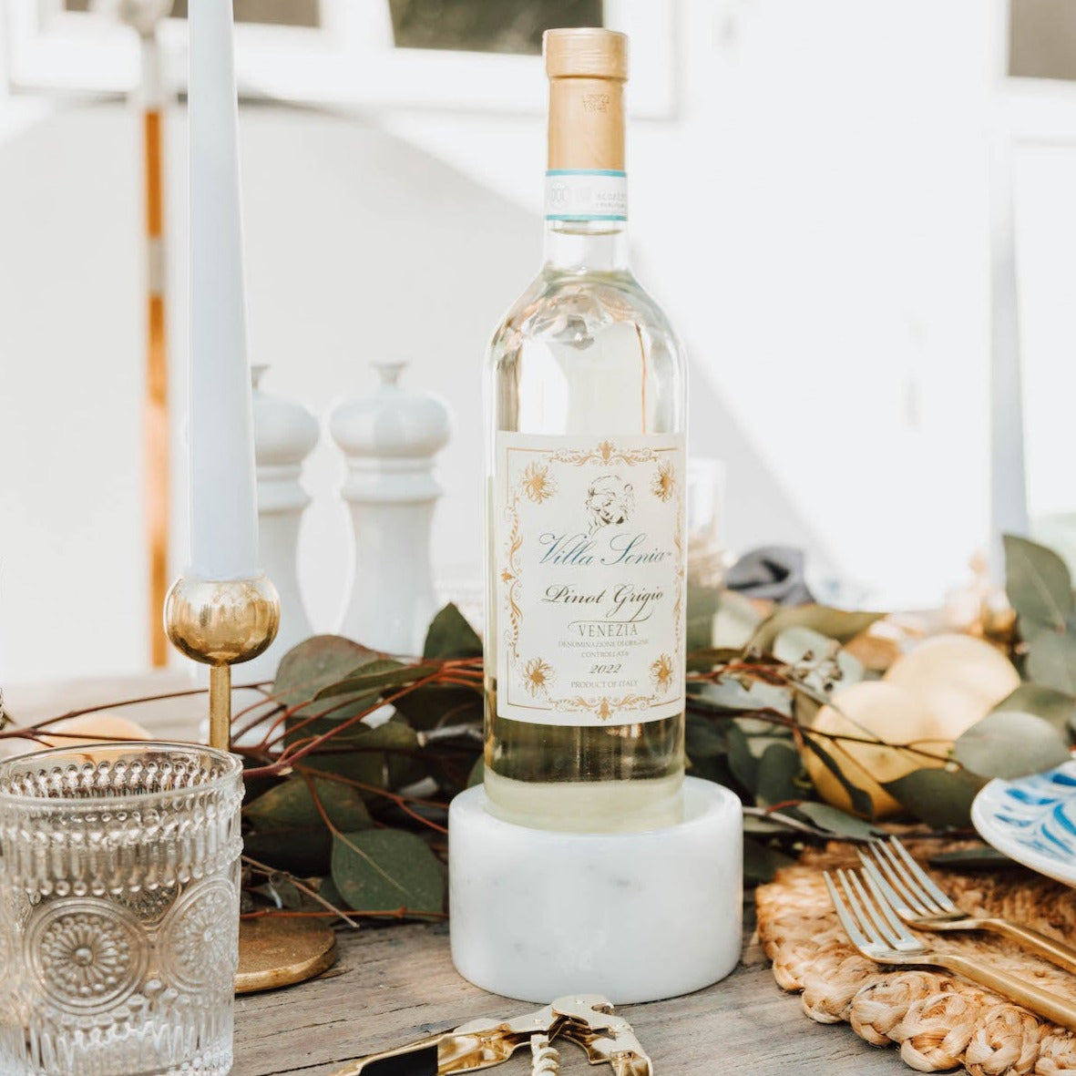 One white marble wine bottle coaster holding a bottle of Sauvignon Blanc on a wooden outdoor table.