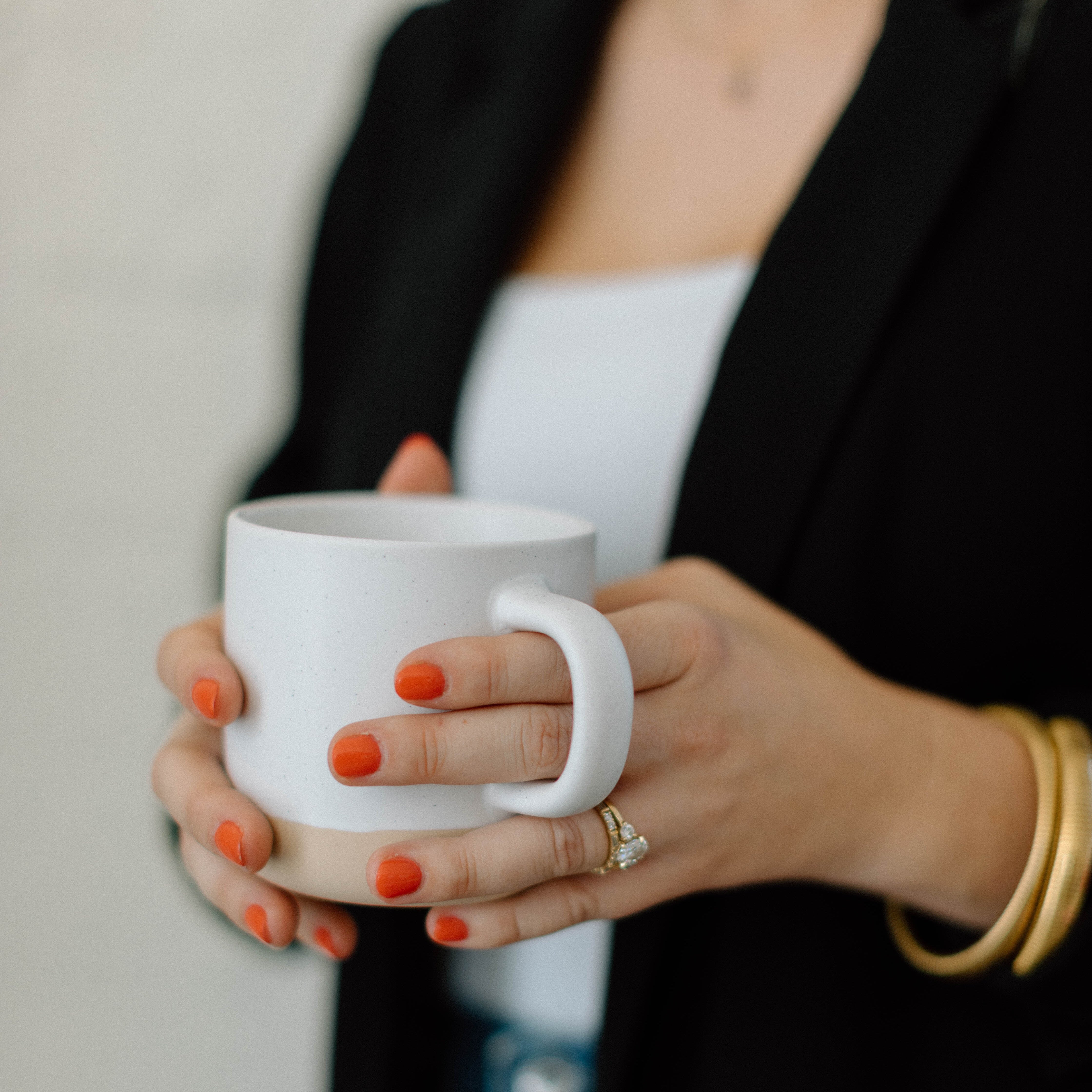 hands holding speckled beige ceramic mug