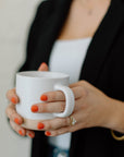 hands holding speckled beige ceramic mug