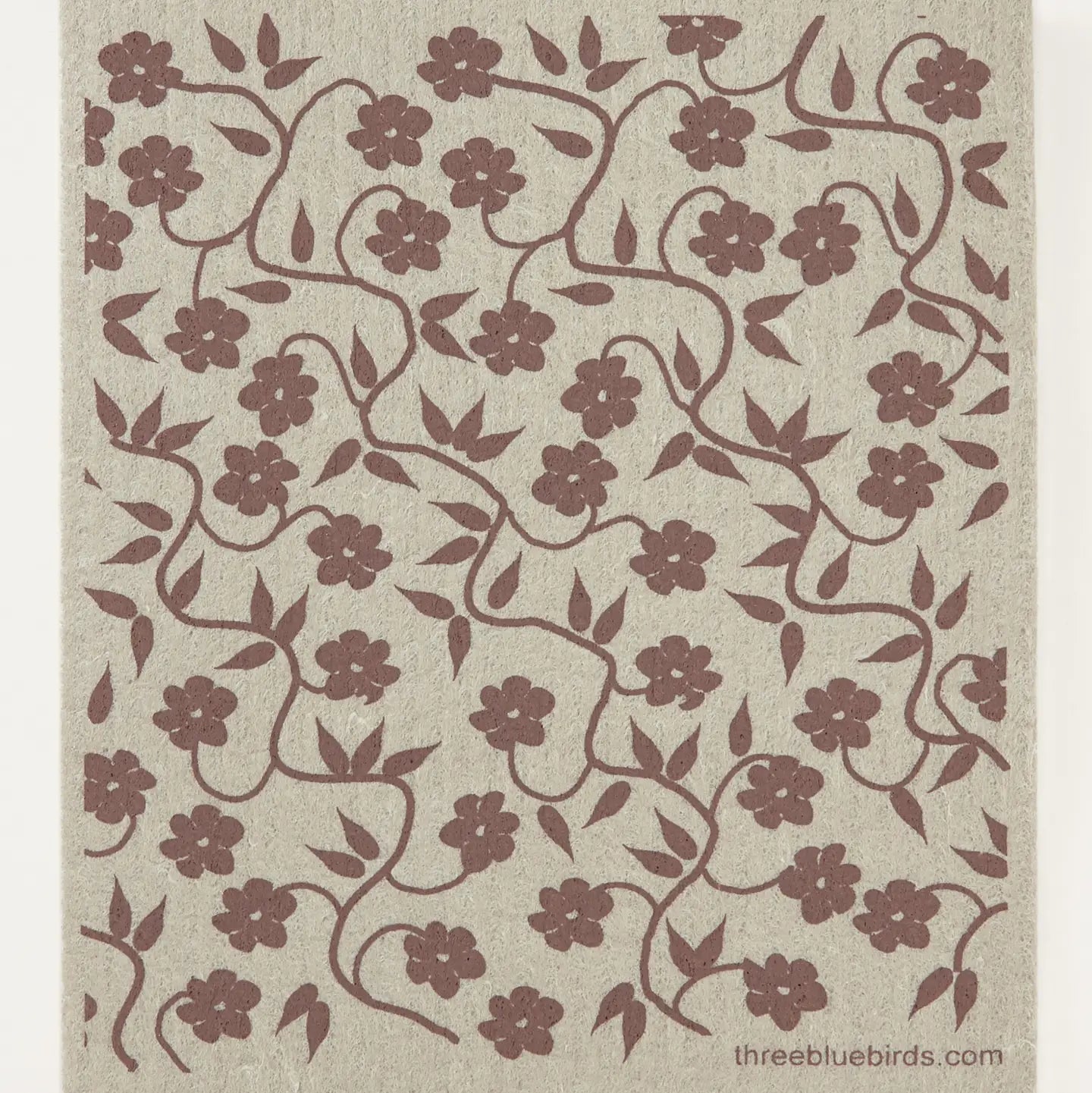 A square textile or rug sample with a repeating floral vine pattern. The design features dark brown flowers and swirling vines on a warm beige textured background.