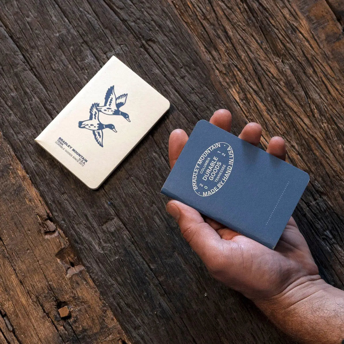 Hand holding a blue card with branding on a wooden surface
