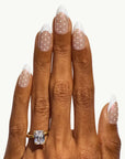 Hand wearing a gold ring with a diamond on a white background