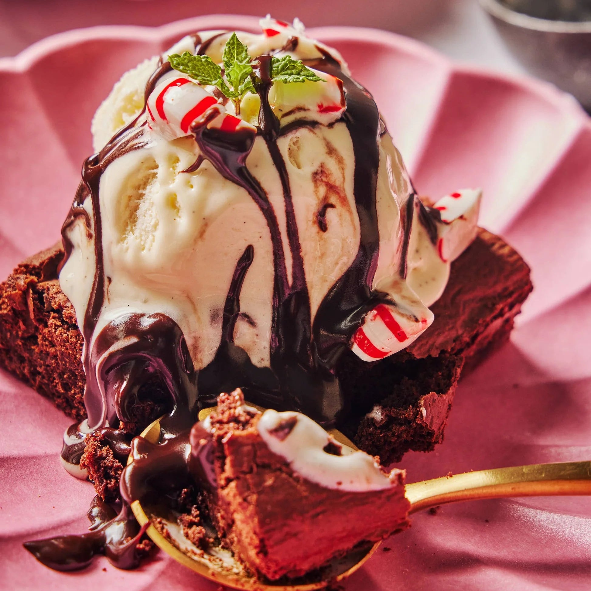 Ice cream sundae with brownie and chocolate drizzle on a pink plate