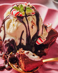 Ice cream sundae with brownie and chocolate drizzle on a pink plate