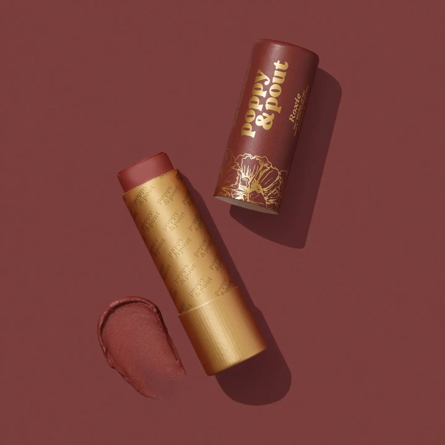 Lipstick with gold casing and brown shade on a matching background, featuring the brand 'Poppy &amp; Point'.