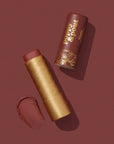 Lipstick with gold casing and brown shade on a matching background, featuring the brand 'Poppy & Point'.