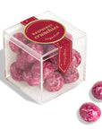 Pink raspberry crunchies candies in a clear cube with a red label on a white background