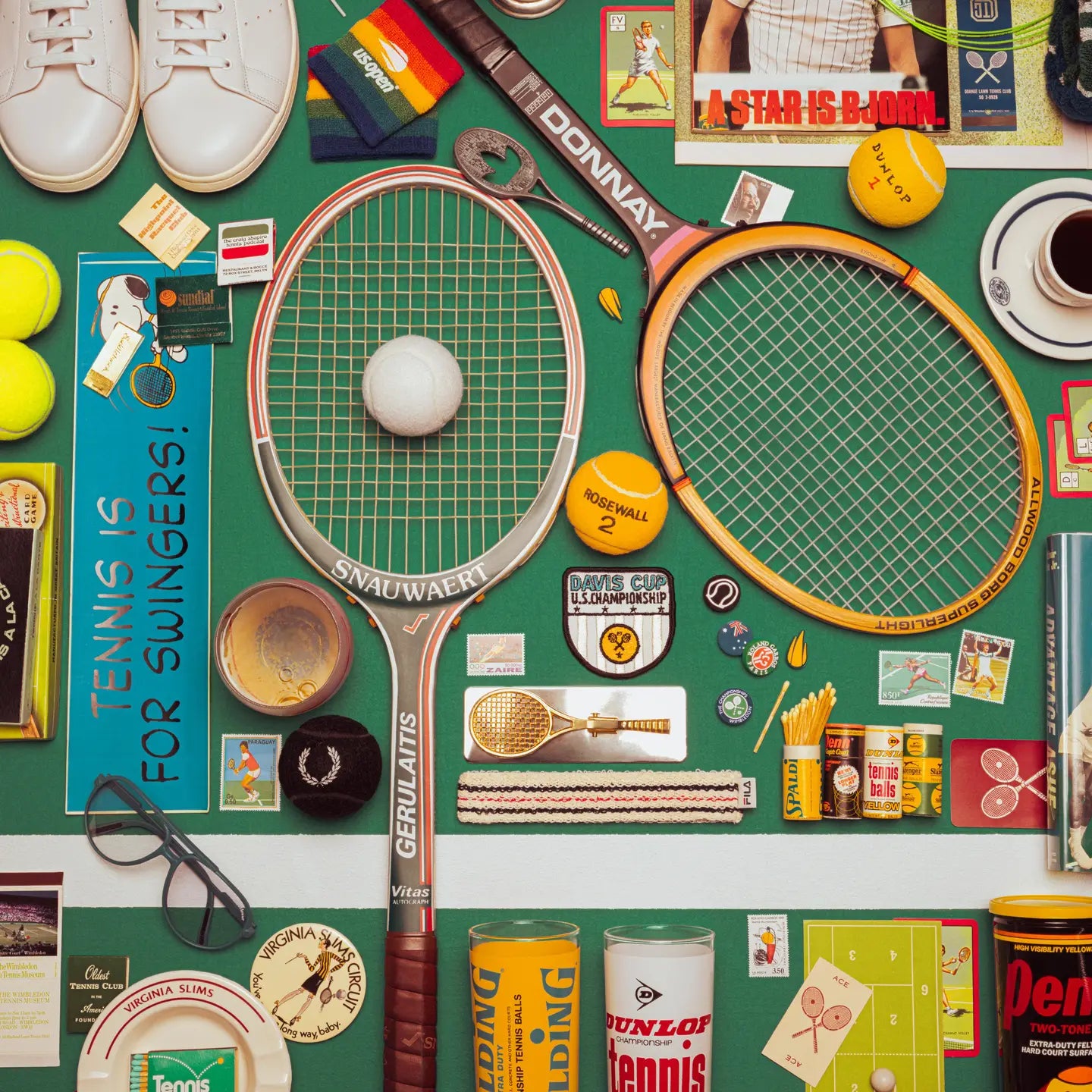 Collection of tennis-themed items including rackets, balls, and vintage-style packaging on a green background.