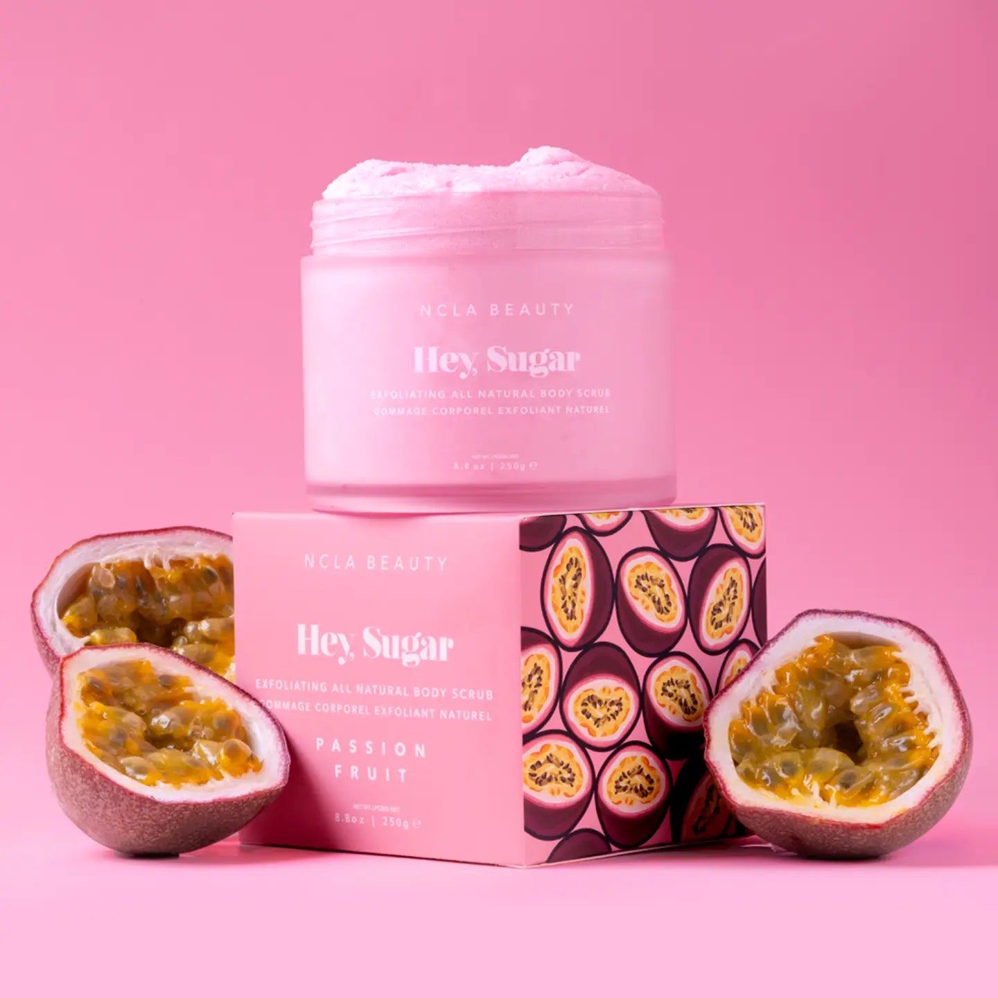 Pink body scrub with packaging and passion fruit on a pink background