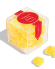 Clear cube container with yellow gummy bears and a red label on a white background
