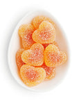 Heart-shaped gummy candies in a white bowl on a white background