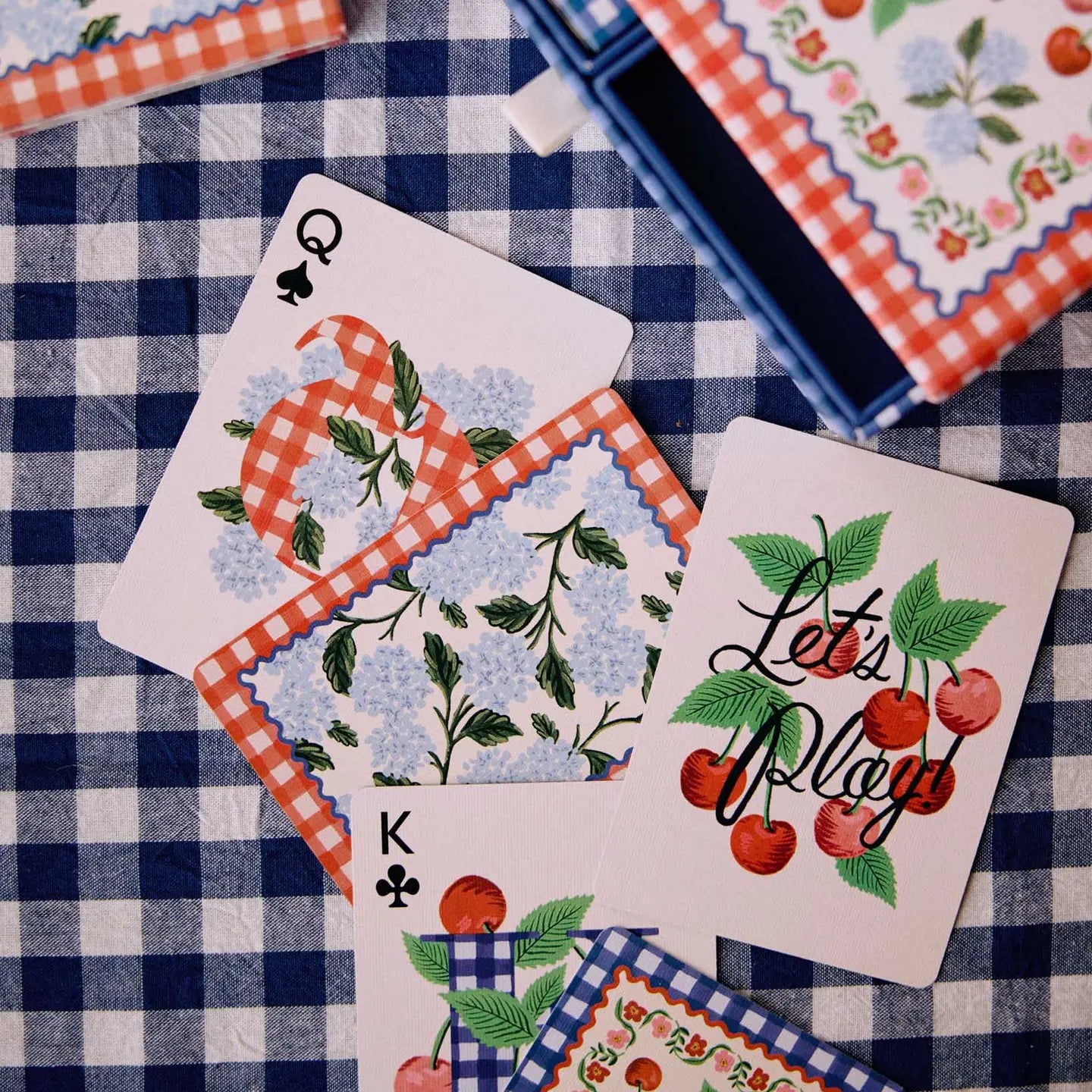 rifle paper co picnic playing cards on a blue gingham tablecloth