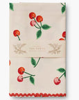 The cherry-patterned tea towel is neatly folded and wrapped in a Rifle Paper Co. branded paper label. The label reads "Tea Towel, 100% Cotton, 21 x 28 inches," showcasing its elegant packaging.

