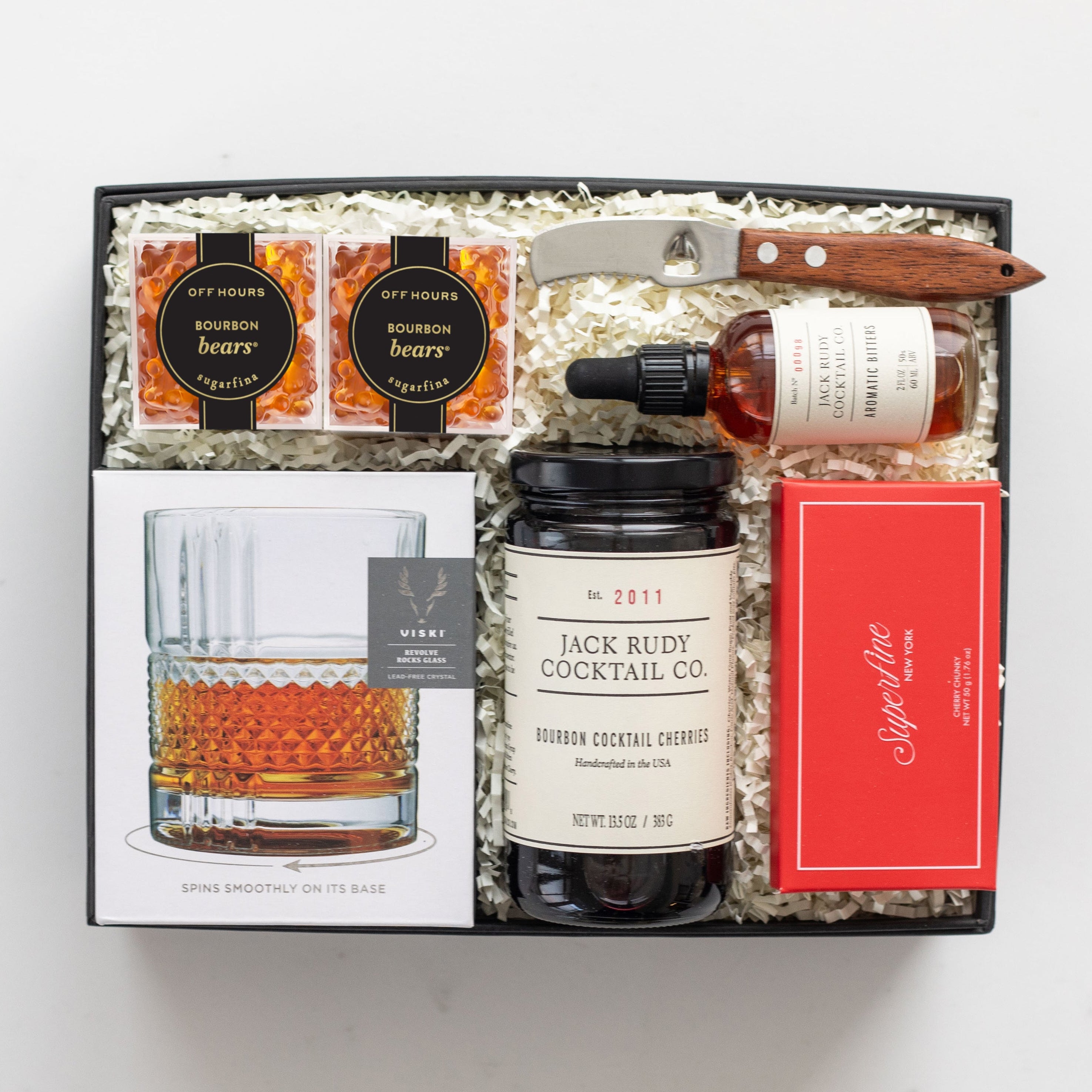 Gift set with bourbon, cocktail mix, and bar tools on a white background