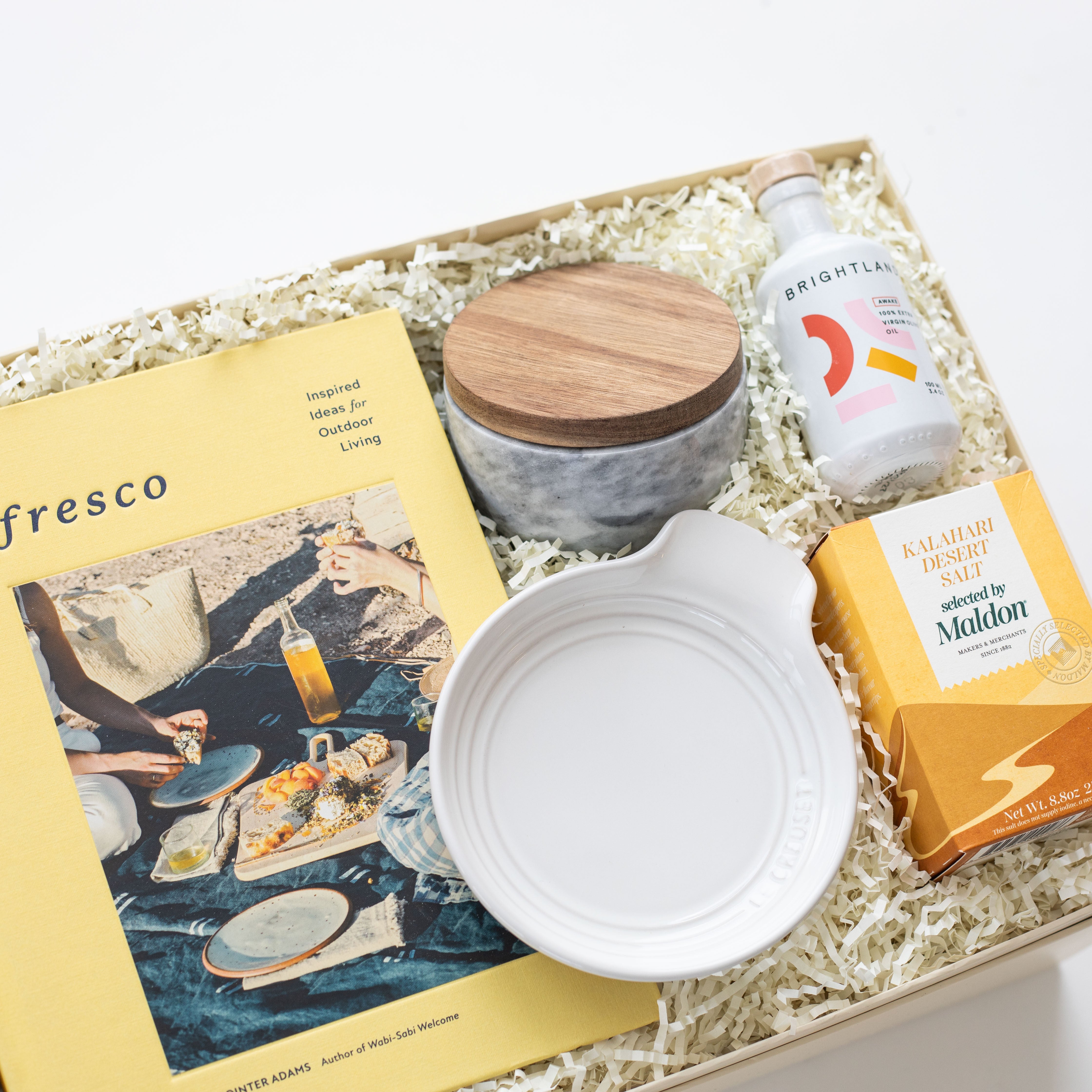 Gift box with a magazine, ceramic items, and a bottle of wine on a white background