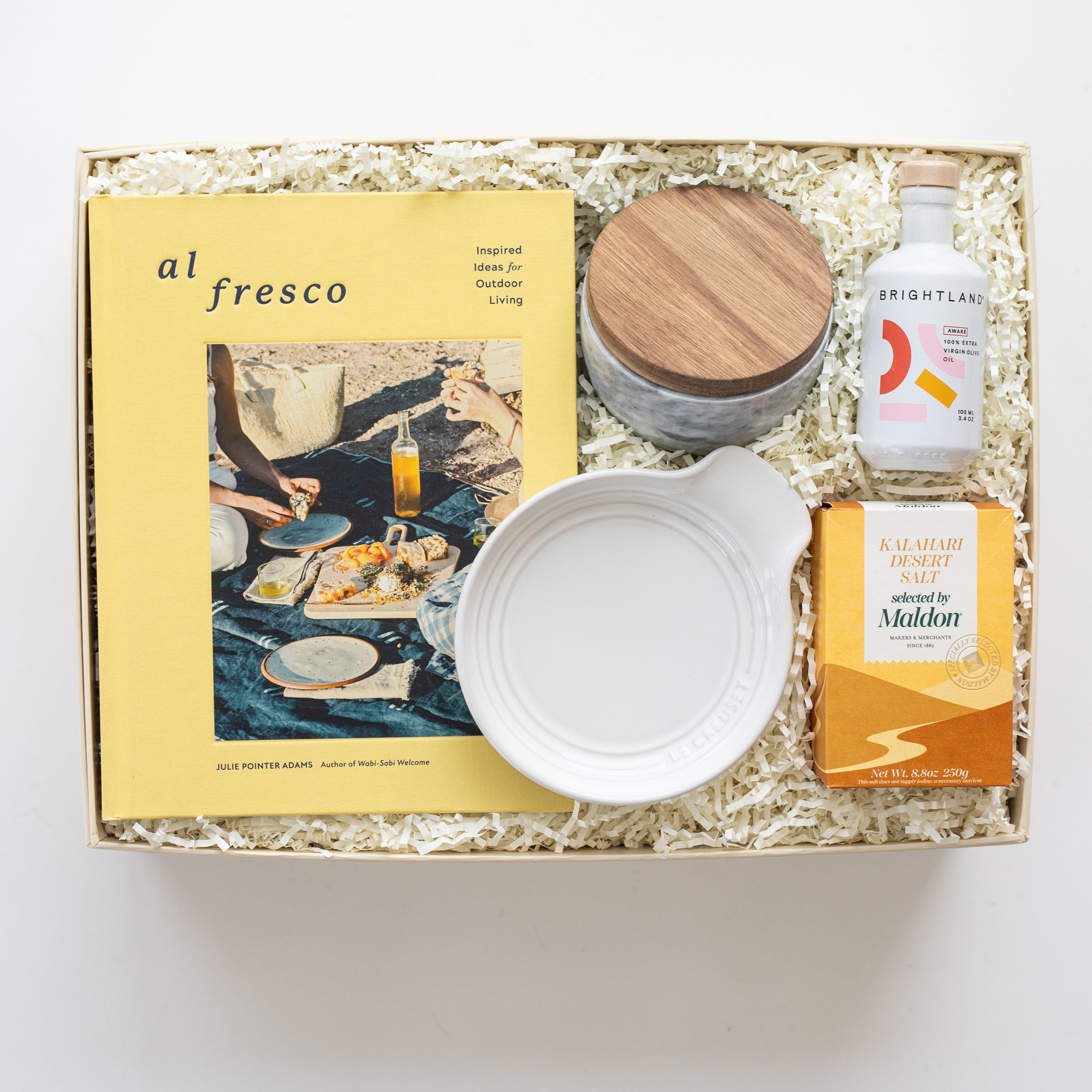 Gift box with 'al fresco' magazine, cutting board, and other items on a white background