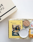 Gift box with 'Box Fox' branding, featuring a magazine, bowls, and a bottle on a white background.