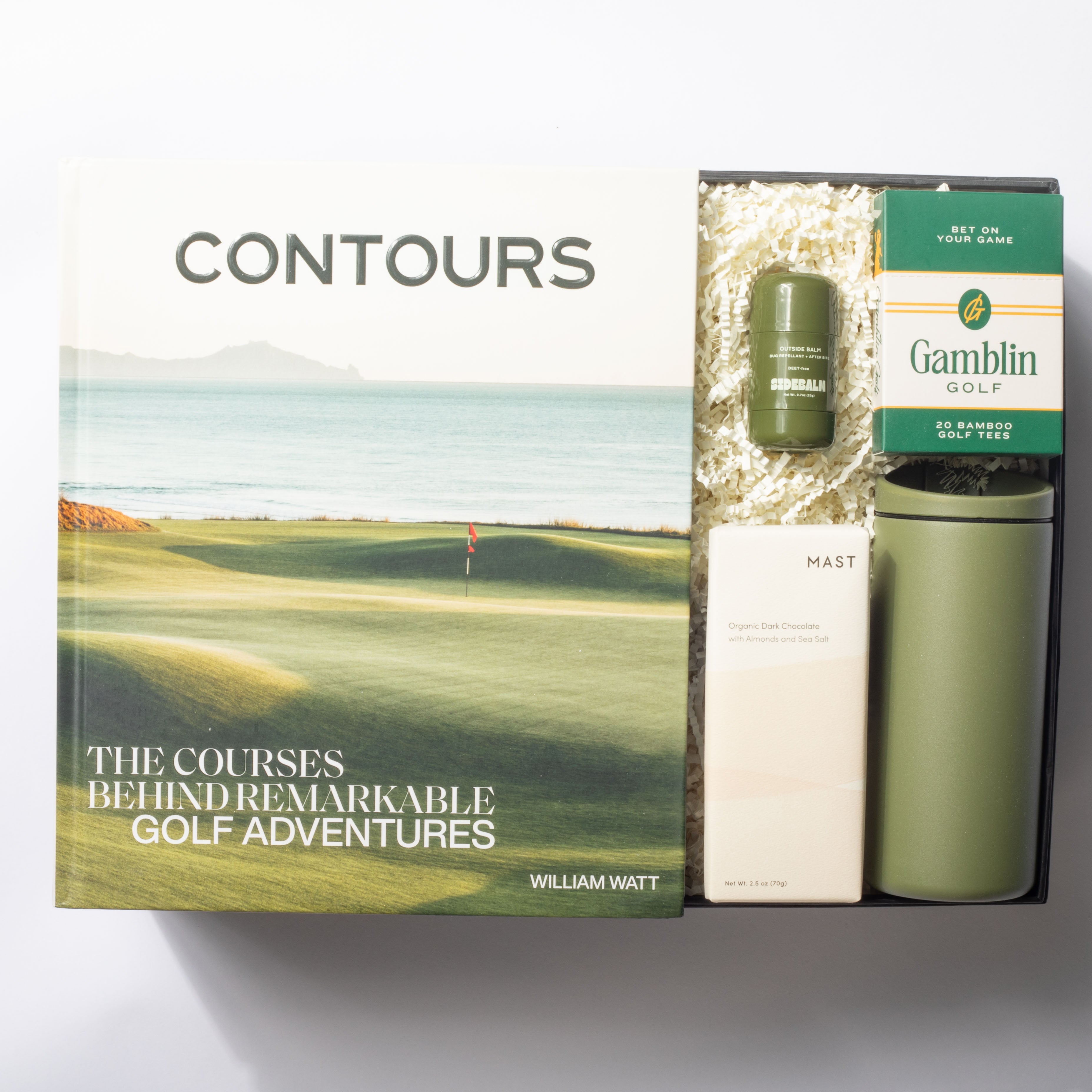 Gift set with 'Contours' book, tumbler, and golf tees on a white background