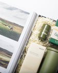Golf-themed gift set with a magazine, green tumbler, and box of Gamblin Golf tees on a white background.