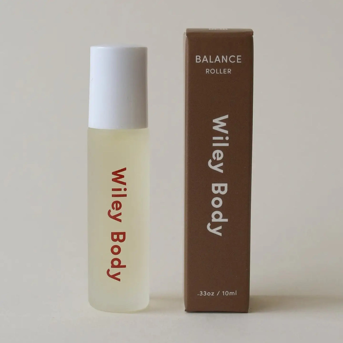 A bottle of Wiley Body Balance Roller next to its brown cardboard packaging box, set against a plain light beige background.