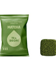 A green bag of Tea Drops Matcha tea drops next to a single square-shaped green tea drop on a plain white background.