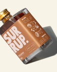 Bottle of Sur Rup syrup with a gold cap on a light background