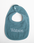 Blue baby bib with 'Watson' embroidered on a white background