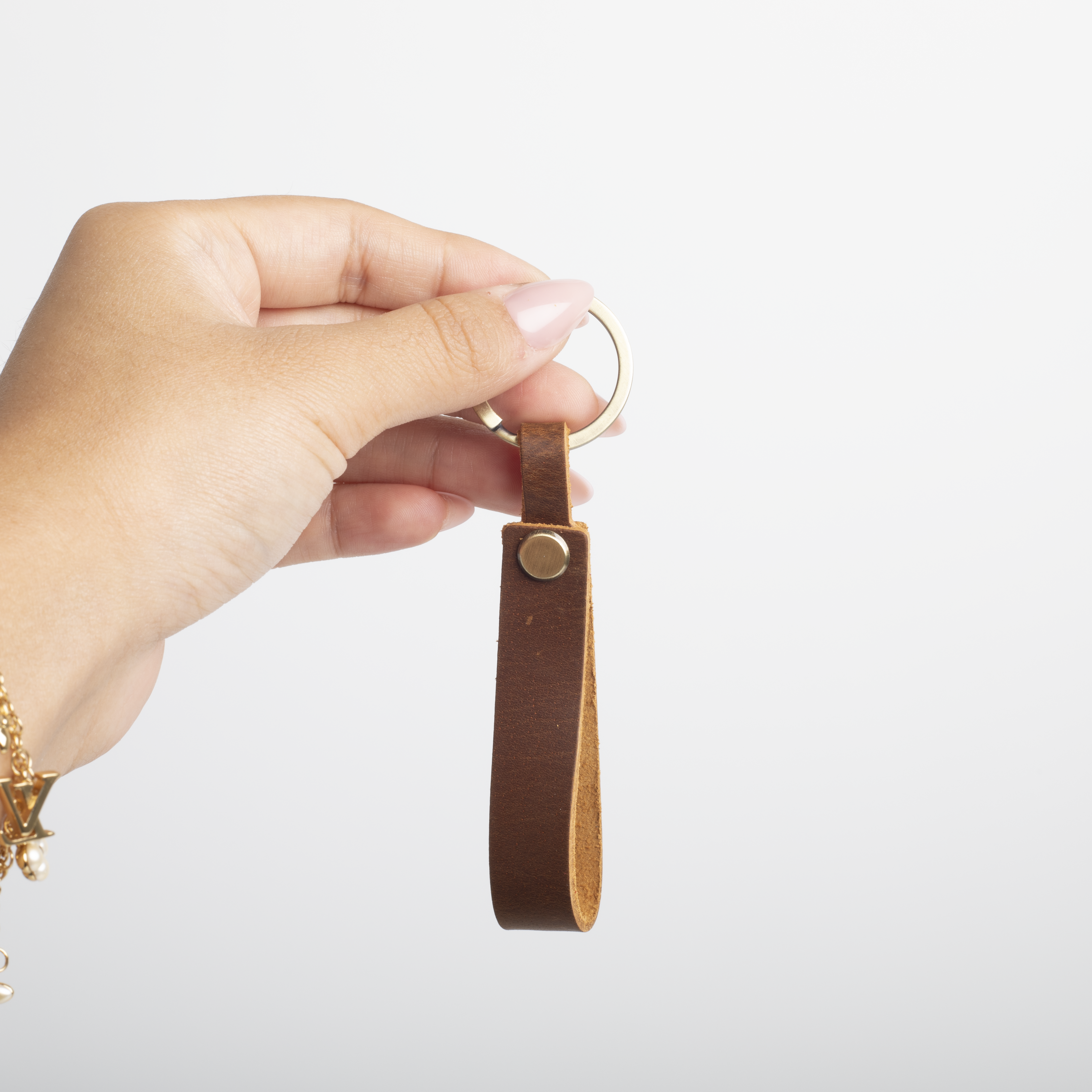 Hand holding a brown leather keychain against a white background