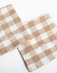 Two checkered towels with embroidered text on a white background