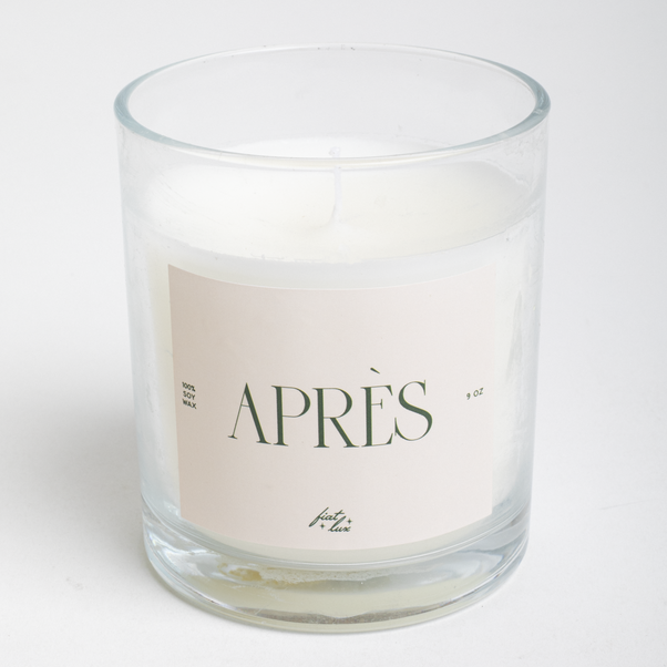 Candle in a glass jar with a 'APRèS' label on a white background
