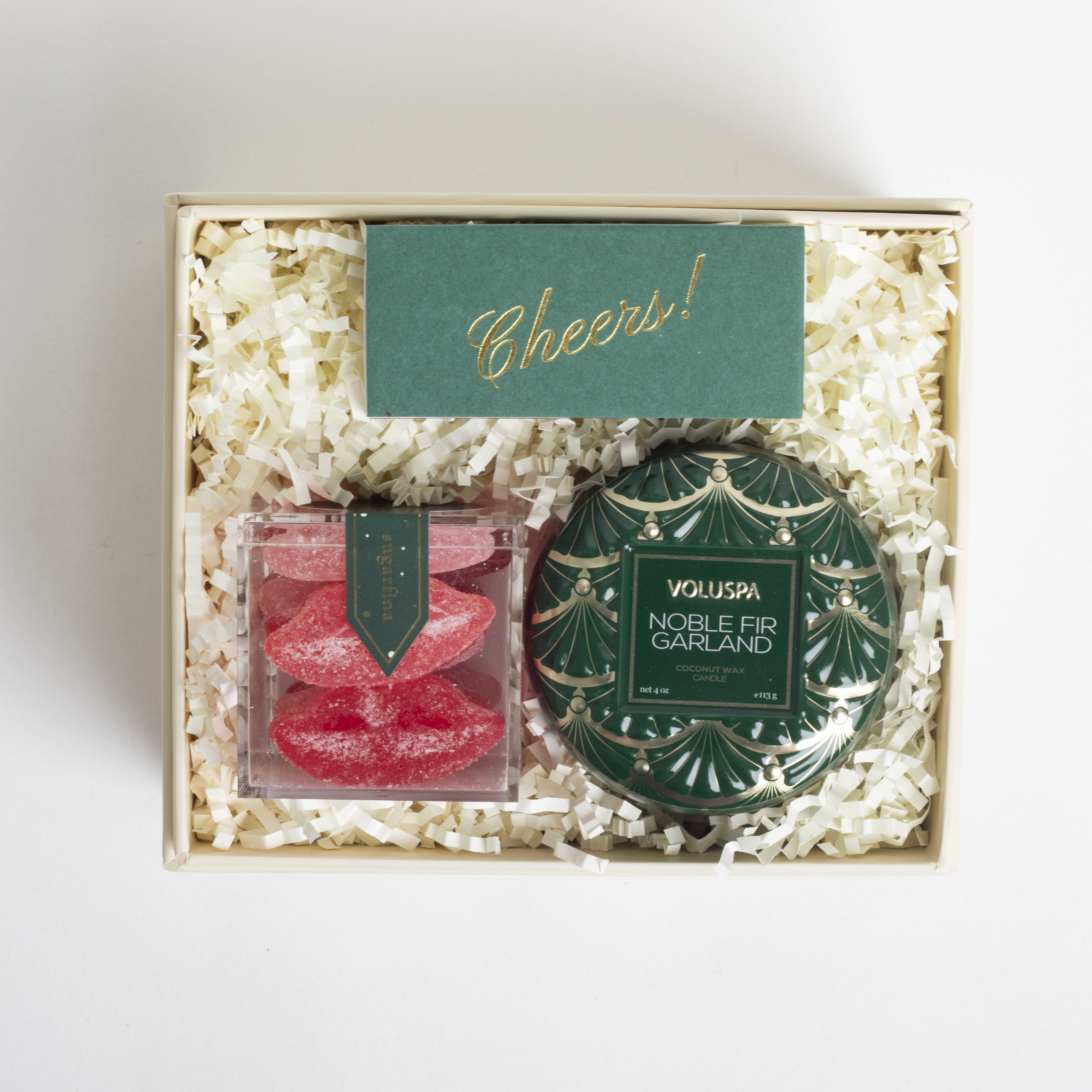 Gift set with a decorative candle and candy in a box labeled 'Cheers!'