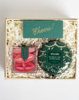 Gift set with a decorative candle and candy in a box labeled 'Cheers!'