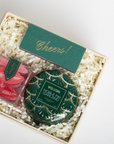 Gift set with Voluspa candle and red candy in a box labeled 'Cheers!'