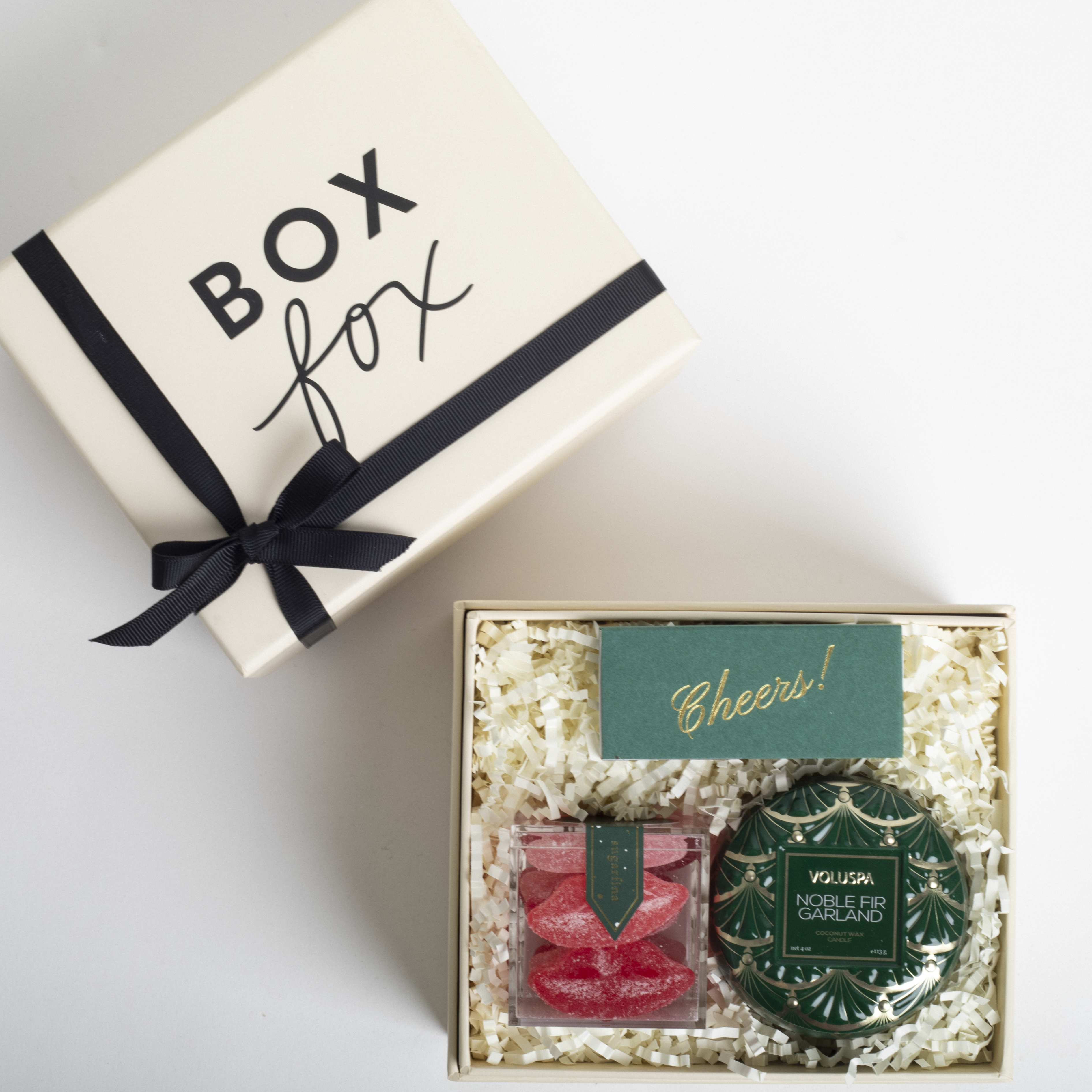 Gift box with 'Box Fox' branding and a 'Cheers!' card, containing decorative items.