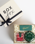 Gift box with 'Box Fox' branding and a 'Cheers!' card, containing decorative items.