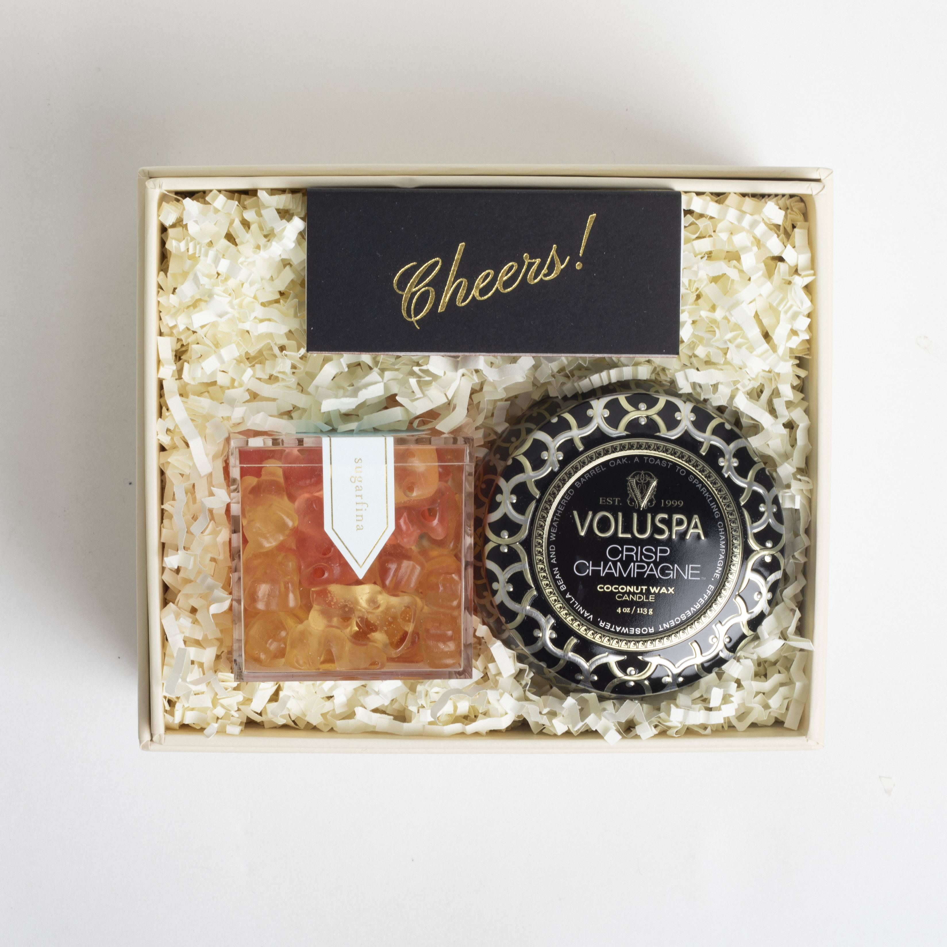 Gift box with Voluspa candle and other items on a light background