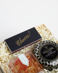Gift set with Voluspa candle, 'Cheers!' card, and small container of gummy bears in a box.
