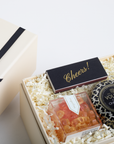 Gift box with gummy bears, chocolate bar, and Voluspa candle on a light background