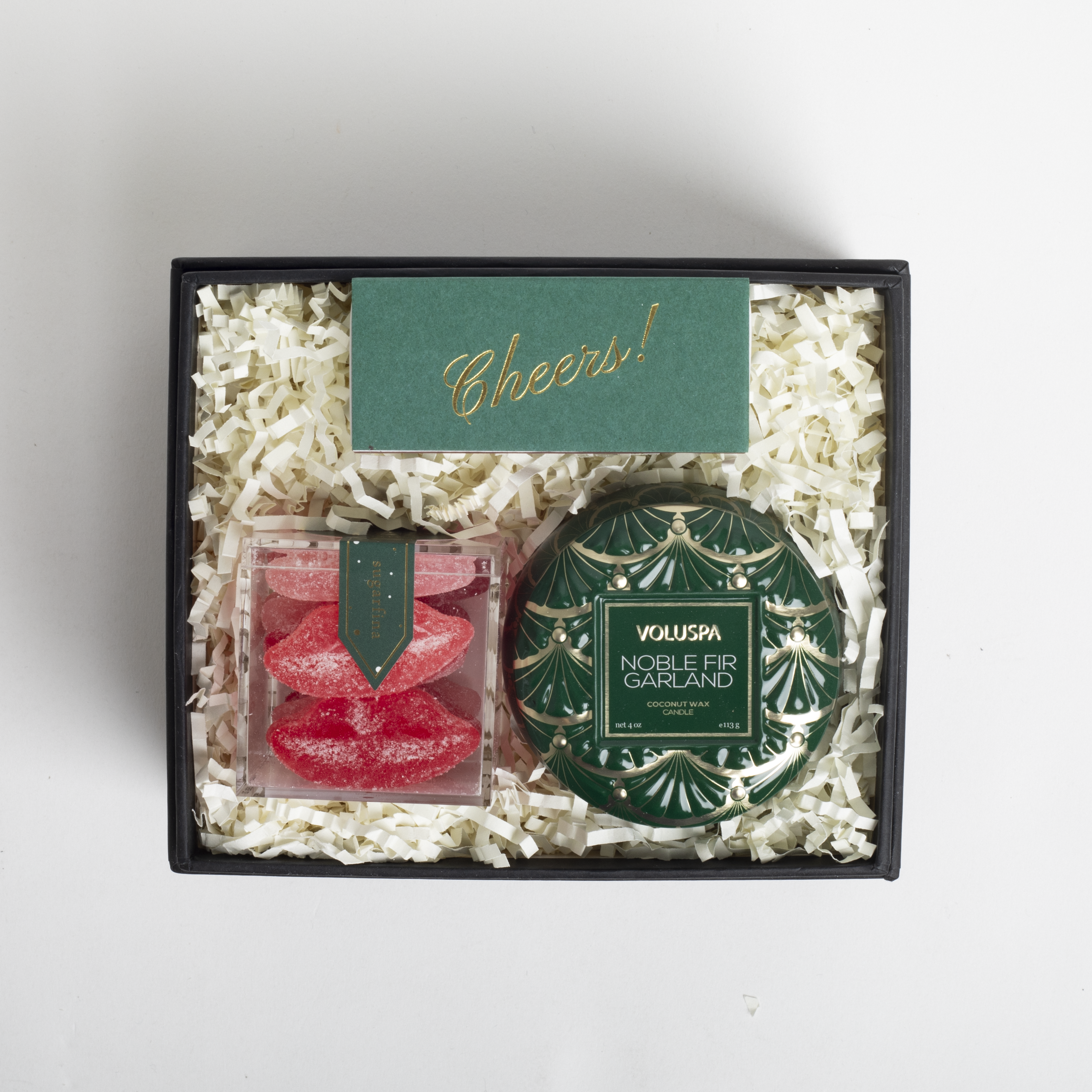 Gift set with Voluspa candle and candy in a box labeled &#39;Cheers!&#39;