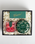 Gift set with Voluspa candle and candy in a box labeled 'Cheers!'