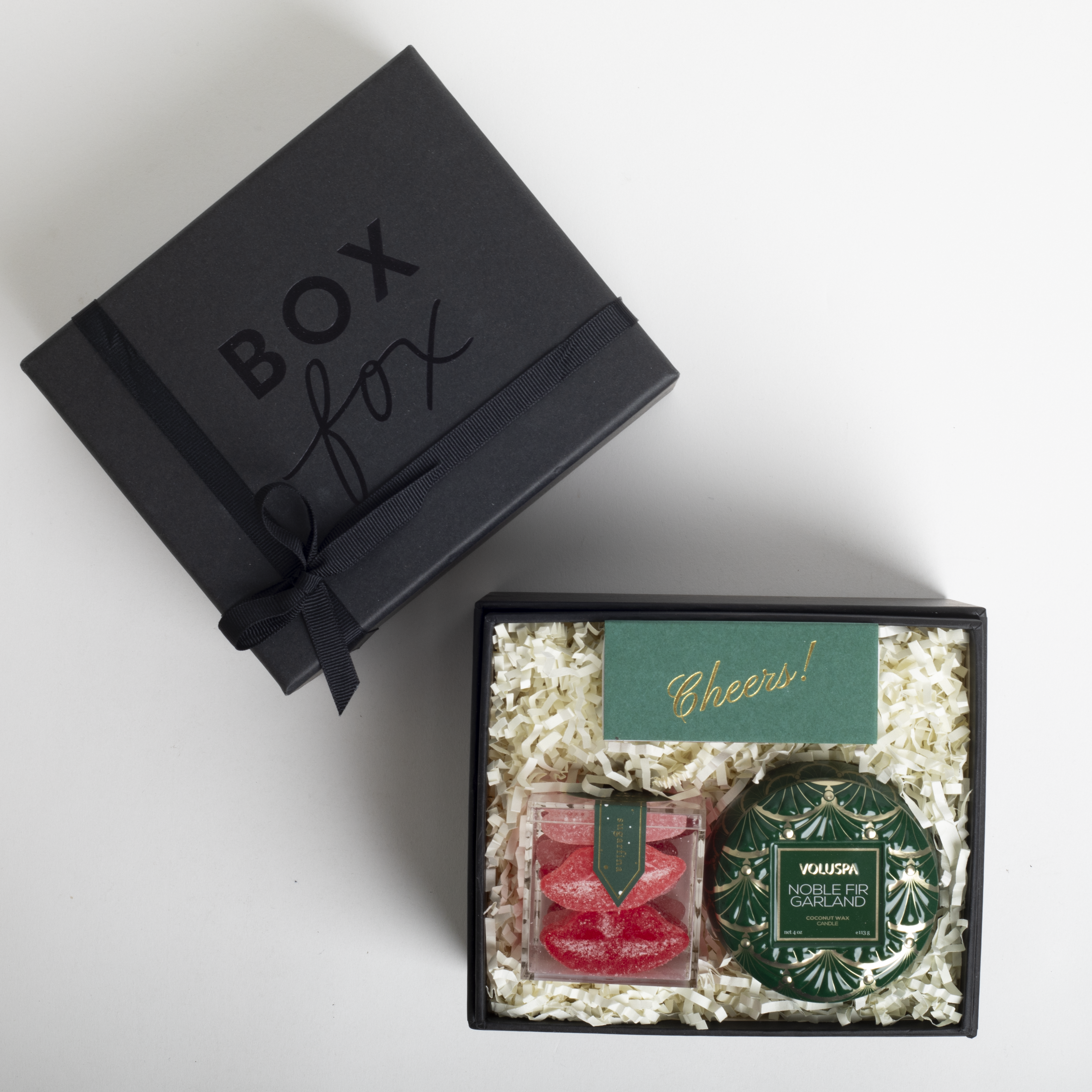 Gift box with &#39;Box Fox&#39; branding, containing a red item and a green decorative item on a white background.