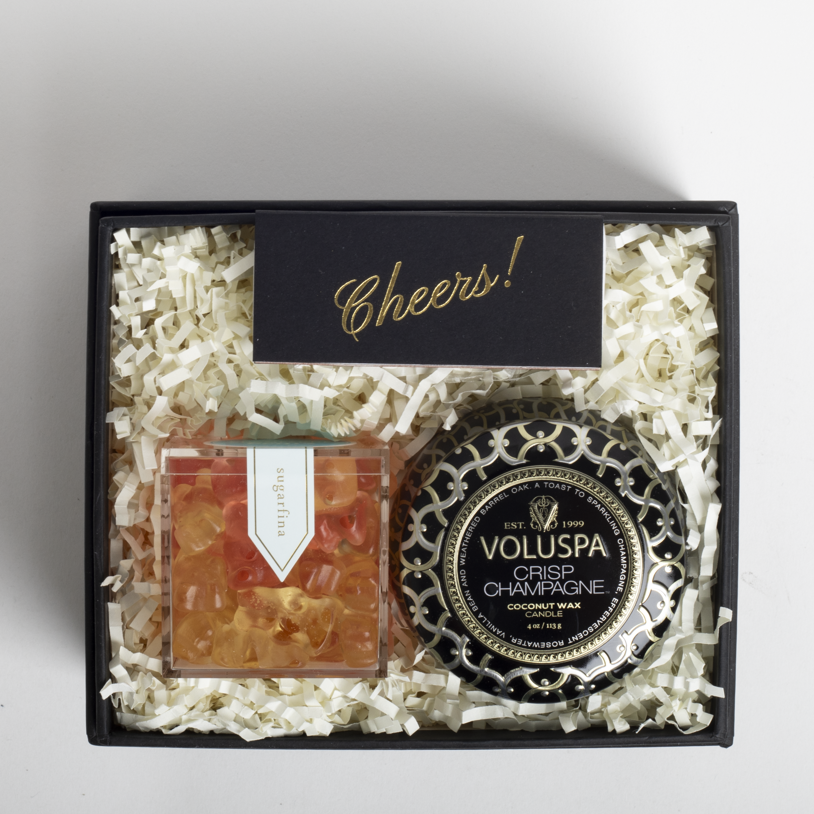 Gift set with Voluspa candle and other items in a black box on a light gray background