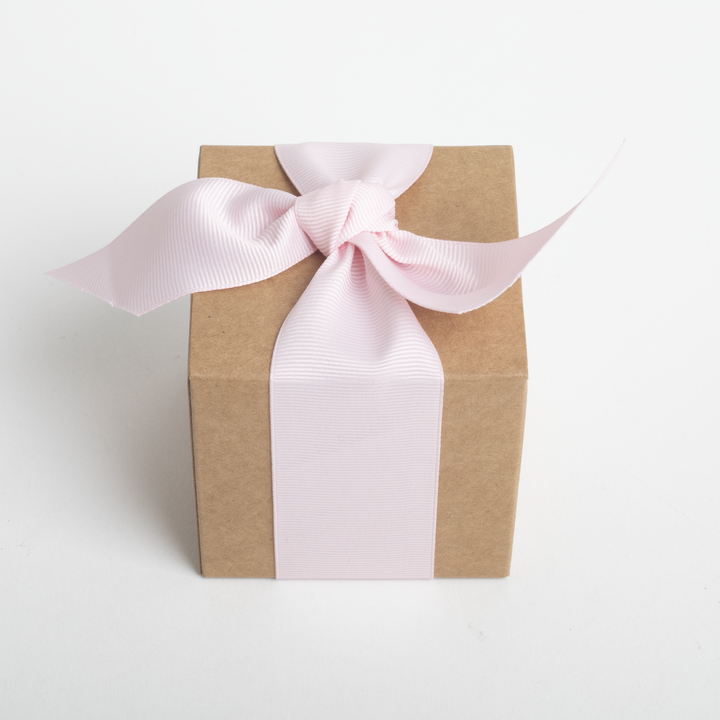 Gift box wrapped in brown paper with a pink ribbon on a white background