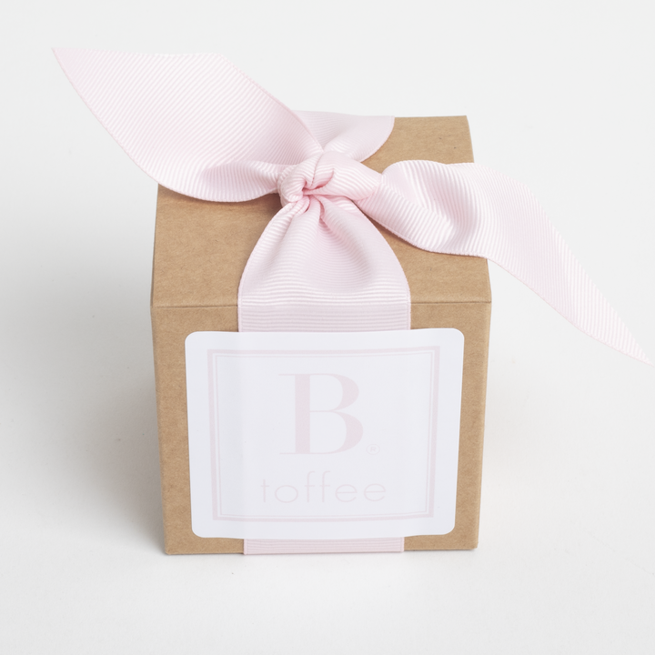 Gift box with a pink ribbon and a white label on a light gray background